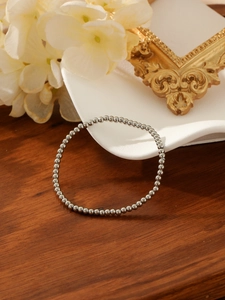 Polished silver metal bead bracelet on a warm wooden surface with elegant decor