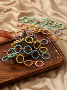 Detailed view of colorful acrylic link bracelets with gold metal rings on silk background