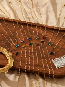 Detail view of colorful emerald-cut zircon pendants on gold paperclip chain necklaces