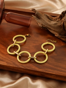 Close-up of yellow acrylic rings and stainless steel links on a decorative wood tray