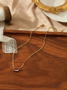 Detail of pink rectangular zircon pendant on a golden paperclip link chain necklace
