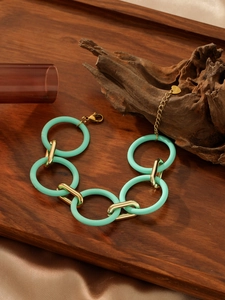 Detailed close-up of mint green acrylic rings and gold stainless steel chain bracelet links
