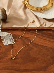 Detail view of gold paperclip chain necklace with faceted yellow gemstone pendant