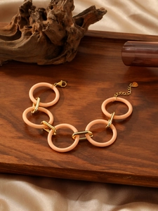 Detail of pink resin and gold metal links with heart charm and lobster clasp closure
