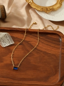 Detailed close-up of a blue rectangle gemstone on a golden paperclip link chain necklace