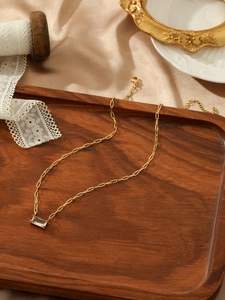 Macro view of gold paperclip chain necklace with a rectangular clear crystal pendant