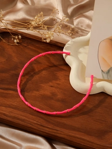 Detailed view of neon pink bamboo-style necklace with gold metal rings on silk fabric
