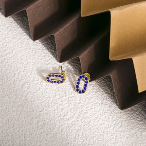 Détail de boucles d'oreilles ovales plaquées or avec zircons bleu foncé sur fond