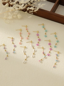 Detailed macro view of handmade daisy beaded long drop earrings in pastel colors