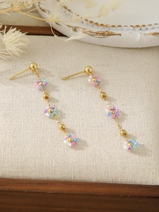 Detail view of long tassel flower earrings with colorful beads and golden chains