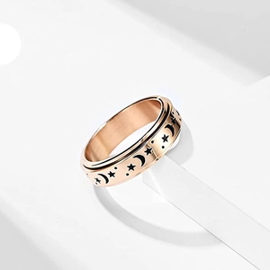Primer plano de anillo giratorio de oro rosa con motivos grabados de estrellas y lunas