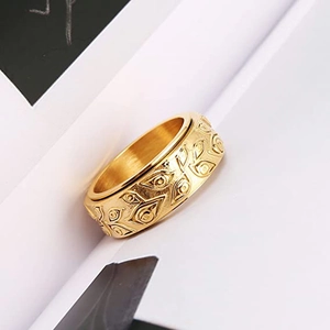 Close-up of golden spinning Eye of Providence ring with relief patterns on white paper