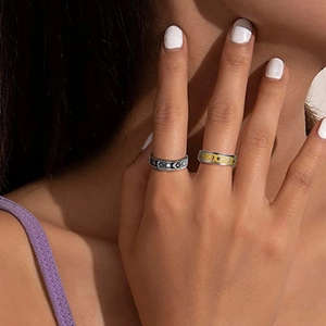 Close-up of bohemian star and moon spinner rings in black and gold on a model finger