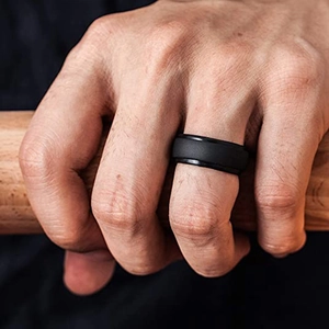 Matte black titanium spinner ring for men with brushed texture and polished edges on wood