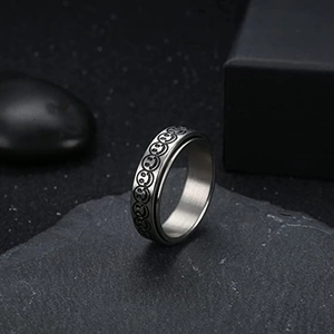 Gros plan d'une bague rotative en acier titane avec motifs de smileys sur roche noire