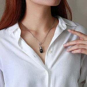 Detalle macro del colgante de cápsula plata y negro con cruz en modelo con camisa
