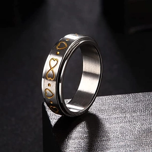 Dettaglio dell'anello rotante a doppio strato con motivi dorati a cuore e infinito