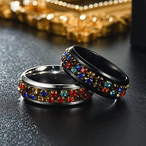 Detail of silver and black stainless steel rings featuring multi-colored rhinestone inlay