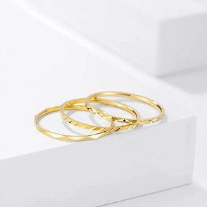 Detailed close-up of three 18K gold textured stacking rings on a white pedestal display