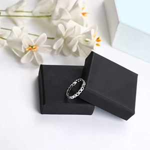 Minimalistische zilveren hartring op zwarte juwelendoos met een florale achtergrond