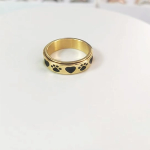 Detail of golden stainless steel spinner ring featuring black heart and paw print motifs