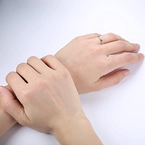Detailopname van een zilveren hartvormige ring gedragen op de vinger tegen witte achtergrond