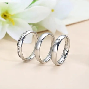 Close-up of three minimalist silver titanium steel rings with diamond accents and polished finish