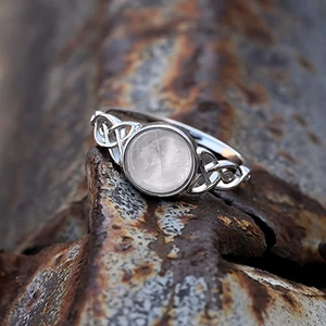 Detaillierte Nahaufnahme eines silbernen Keltenknoten-Rings mit Mondstein auf Rostfläche
