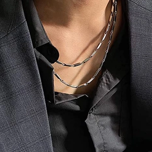 Detail of silver stainless steel rectangular link chain worn on a grey suit jacket