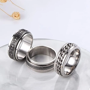 Close-up of three silver stainless steel rings with geometric patterns and chain details