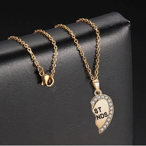 Detailed shot of a gold heart pendant with white crystals and ST NDS engraving