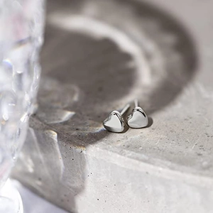 Detalle de los pendientes de corazón en acero de titanio pulido sobre base de piedra