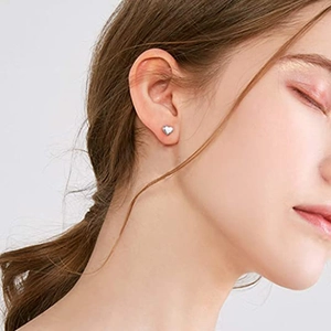 Primer plano de un pendiente de corazón plateado minimalista en la oreja para un look refinado