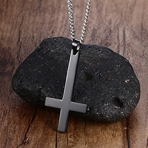 Gros plan sur un pendentif croix renversée en métal mat sur fond de pierre sombre