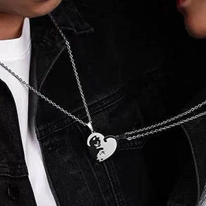 Close-up of couples cat puzzle necklace set showing heart-shaped black and white pendants