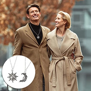 Close-up of vintage sun and moon pendant necklaces worn by a couple on a street
