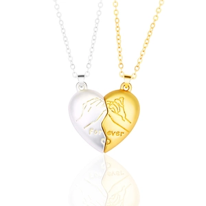 Detail of silver and gold magnetic heart pendants with pinky swear engraving for lovers