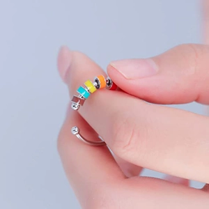 Detalle de anillo giratorio de acero plateado con cuentas de esmalte de colores en mano
