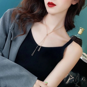Detail of a gold Y-shaped minimalist necklace with triangular tassels on a black sweater