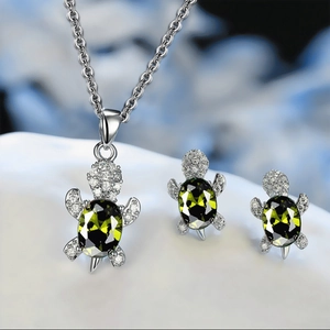 Detailed close-up of sea turtle jewelry set with green stones and silver finish