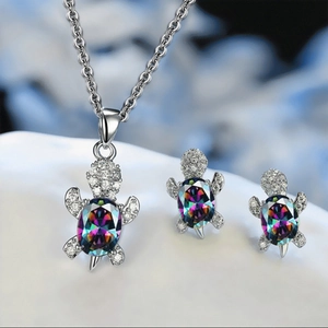 Macro shot of silver turtle necklace and earrings set with iridescent gemstones