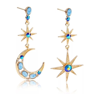 Close-up of asymmetric gold star and moon earrings with blue crystals on white background