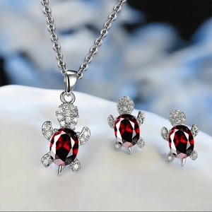 Detailed close-up of turtle jewelry set featuring vibrant red crystals and silver plating