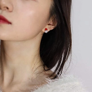 Cute Christmas snowman stud earrings with red enamel hat and white stones worn by a model