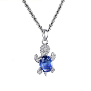 Macro shot of silver turtle pendant with deep blue gemstone and sparkling zircon stones