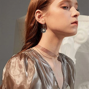 Détail d'une boucle d'oreille soleil rétro avec perle blanche portée par un mannequin
