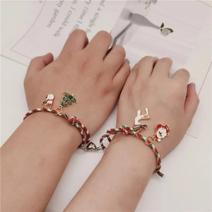 Detalle de pulseras de Navidad tejidas para parejas con imanes de corazón y dijes esmaltados