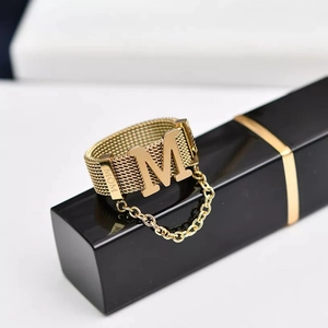 Macro detail of gold grid ring with M initial, MOM engraving and small chain charm