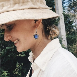 Gros plan de boucles d'oreilles soleil en argent vintage avec pierre de lune bleue