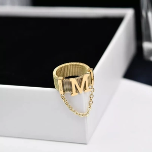 Macro view of gold mesh ring featuring M initial and fine MOM engraved detail with chain